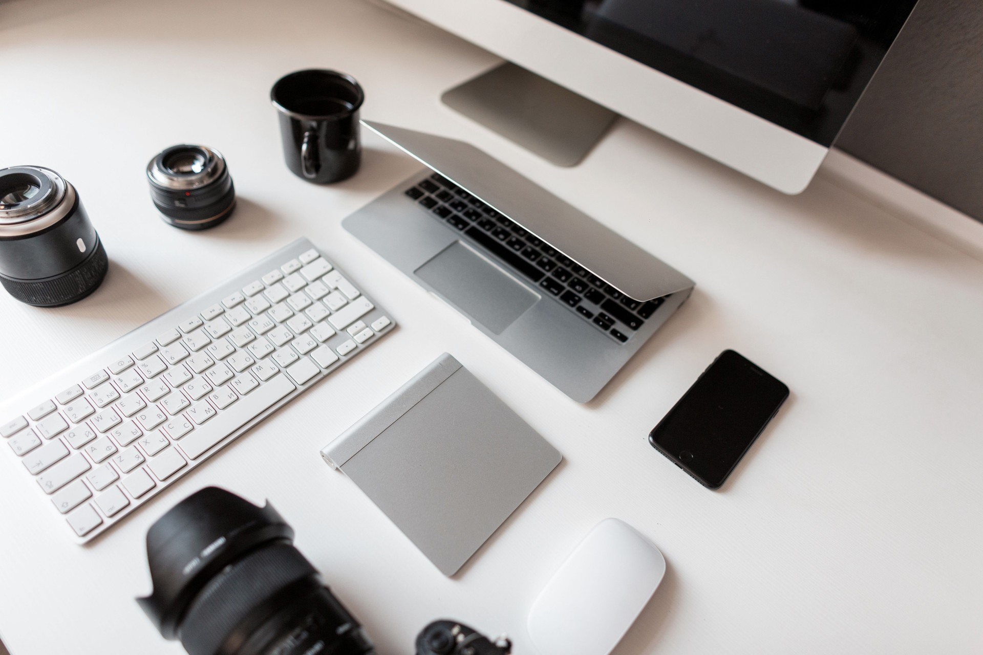 Desktop of the young designer with a laptop with a mouse with a modern professional photo camera with a keyboard with a laptop. Group of objects isolated on a white background. Stylish workplace.